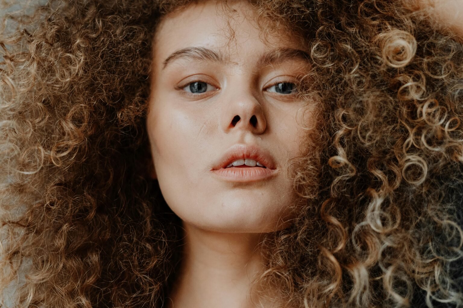 Stunning close-up portrait of a young woman with curly hair, showcasing natural beauty.